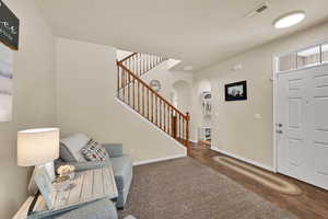 Entryway with arched walkways, stairway, and wood finished floors