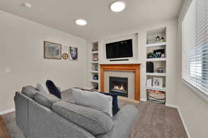 Carpeted living area featuring a fireplace and built in shelves