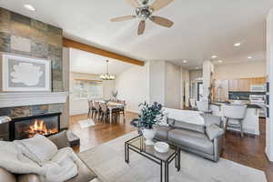 Living area featuring recessed lighting, dark wood-type flooring, a fireplace, ceiling fan, and a chandelier