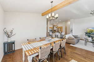 Dining space with beamed ceiling, dark updated wood floors, a ceiling fan, recessed lighting, and a chandelier