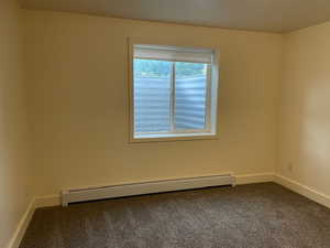 Carpeted spare room featuring baseboard heating and baseboards