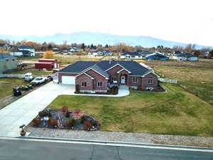 View of front facade with driveway, brick siding, a mountain view, an attached garage, and a residential view