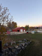 Yard at dusk with an outdoor structure, a pole building, and a garage