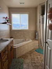 Bathroom with plenty of natural light, a whirlpool tub, vanity, and a textured ceiling