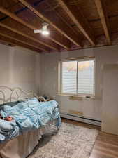 Bedroom featuring a baseboard heating unit, wood finished floors, and a ceiling fan