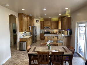 Kitchen featuring brown cabinets, arched walkways, a peninsula, stainless steel appliances, and recessed lighting