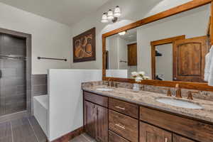 Full bath featuring a garden tub, double vanity, and tiled shower