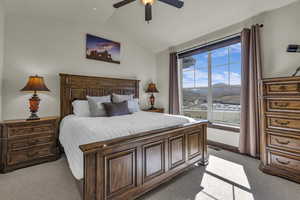Bedroom featuring light colored carpet, vaulted ceiling, a mountain view, and ceiling fan