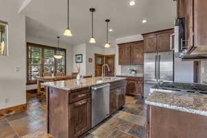 Kitchen featuring backsplash, light stone counters, recessed lighting, pendant lighting, and appliances with stainless steel finishes