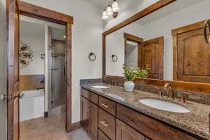 Bathroom featuring a bath, light tile patterned flooring, double vanity, and a stall shower