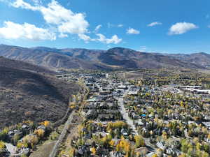 Aerial view of property and surrounding area with nearby suburban area and a mountain backdrop