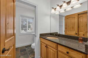 Half bathroom featuring vanity and dark stone finish floors