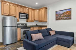 Kitchen with appliances with stainless steel finishes, open floor plan, recessed lighting, dark stone finish flooring, and dark stone counters
