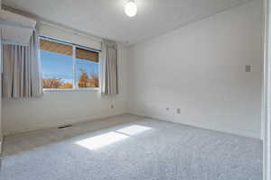 Carpeted empty room with a textured ceiling and baseboards