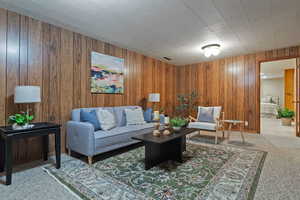 Carpeted living room with wooden walls
