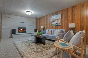Carpeted living area featuring a large fireplace and wood walls