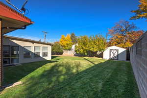 Fenced backyard featuring a storage shed
