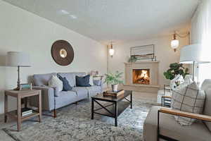 Living area featuring a textured ceiling and a warm lit fireplace