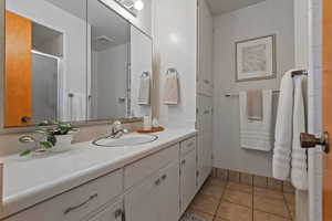 Bathroom with light tile patterned flooring, vanity, and a stall shower