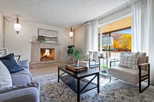 Living room with a textured ceiling, a high end fireplace, and carpet