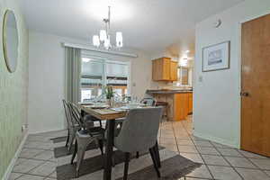 Dining space with light tile patterned flooring, a textured ceiling, and a chandelier