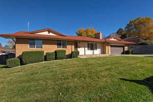 Ranch-style home featuring a front lawn, brick siding, an attached garage, and driveway