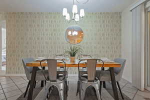 Dining space with light tile patterned flooring, a chandelier, and a textured ceiling