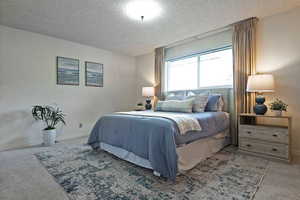 Carpeted bedroom featuring a textured ceiling and baseboards
