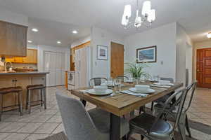Dining room with light tile patterned floors, a chandelier, and recessed lighting