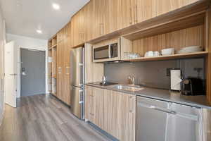 Kitchen with open shelves, stainless steel appliances, modern cabinets, light wood-style flooring, and recessed lighting