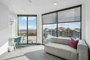 Living area with floor to ceiling windows, carpet, a mountain view, and a residential view