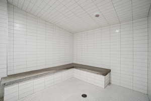 Full bathroom with a sauna, a tile shower, vaulted ceiling, and tile patterned flooring