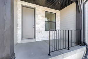 Property entrance with stone siding and a porch