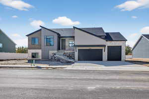View of front of property with concrete driveway, roof with shingles, and a garage