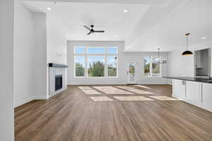 Unfurnished living room with a tile fireplace, light wood-style flooring, recessed lighting, ceiling fan, and a chandelier