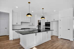 Kitchen featuring white cabinets, backsplash, hanging light fixtures, recessed lighting, and multiple ovens