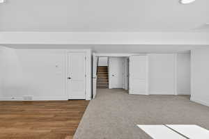Bonus room with stairs, light wood-style flooring, and light carpet
