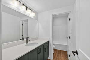 Full bath featuring vanity, dark wood finished floors, and washtub / shower combination