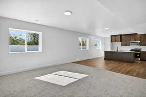 Unfurnished living room featuring dark carpet and baseboards