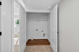 Laundry area featuring dark carpet, electric dryer hookup, washer hookup, and dark wood-type flooring