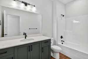Bathroom featuring dark wood-style floors, vanity, and bathtub / shower combination