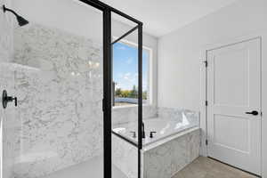 Bathroom featuring a bath, a marble finish shower, and light tile patterned floors
