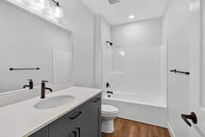 Bathroom with dark wood finished floors, bathtub / shower combination, and vanity