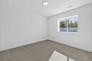 Carpeted spare room featuring baseboards