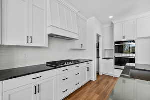 Kitchen featuring dark wood finished floors, appliances with stainless steel finishes, white cabinets, decorative backsplash, and recessed lighting