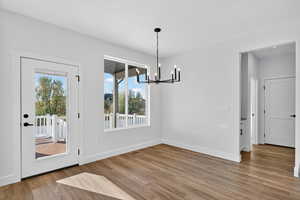 Unfurnished dining area with a chandelier and light wood-type flooring