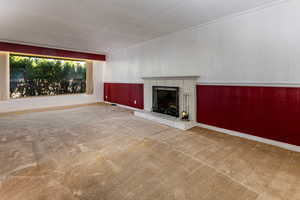 Unfurnished living room with a fireplace, carpet flooring, wainscoting, and wood walls