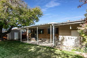 Back of house featuring a storage shed, a patio, brick siding, and a chimney