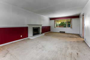 Unfurnished living room featuring light colored carpet, a brick fireplace, and crown molding