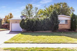 View of front of house with driveway, a front yard, a garage, and brick siding